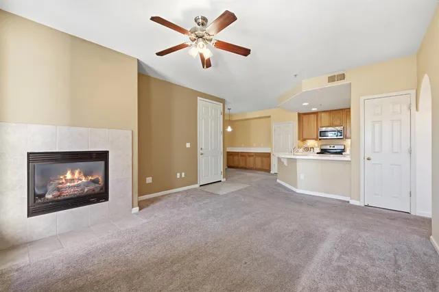 a view of an empty room and kitchen with fireplace