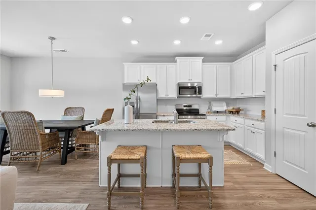 a kitchen with stainless steel appliances granite countertop a table chairs sink refrigerator and cabinets