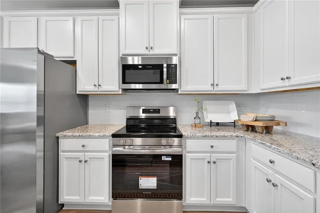 a kitchen with granite countertop white cabinets and stainless steel appliances