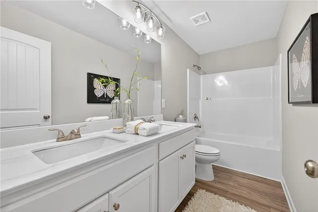 a bathroom with a double vanity sink toilet mirror and bathtub