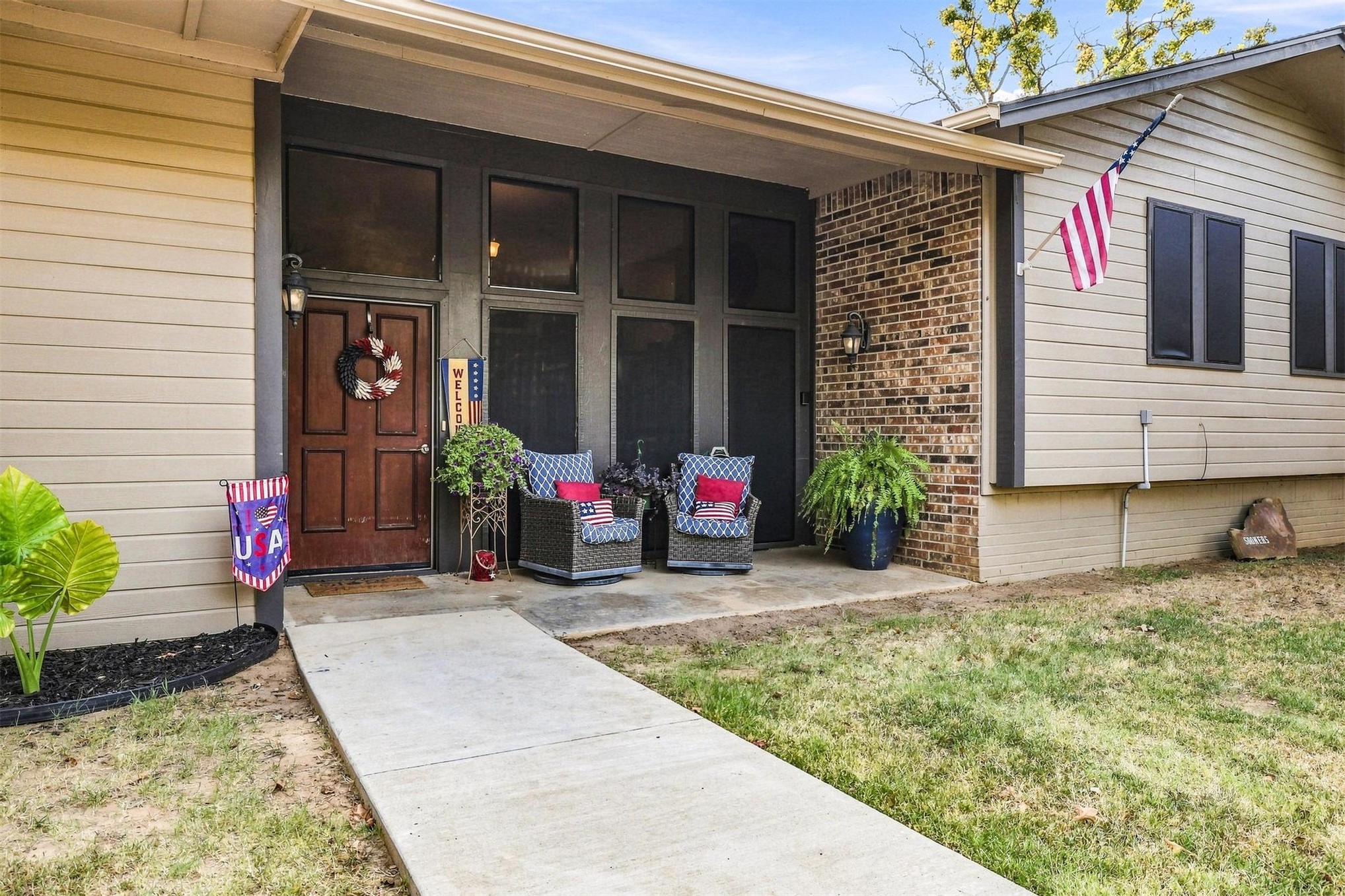 Inviting front entry featuring a solid wood door, brick accents, concrete walkway, and horizontal siding
