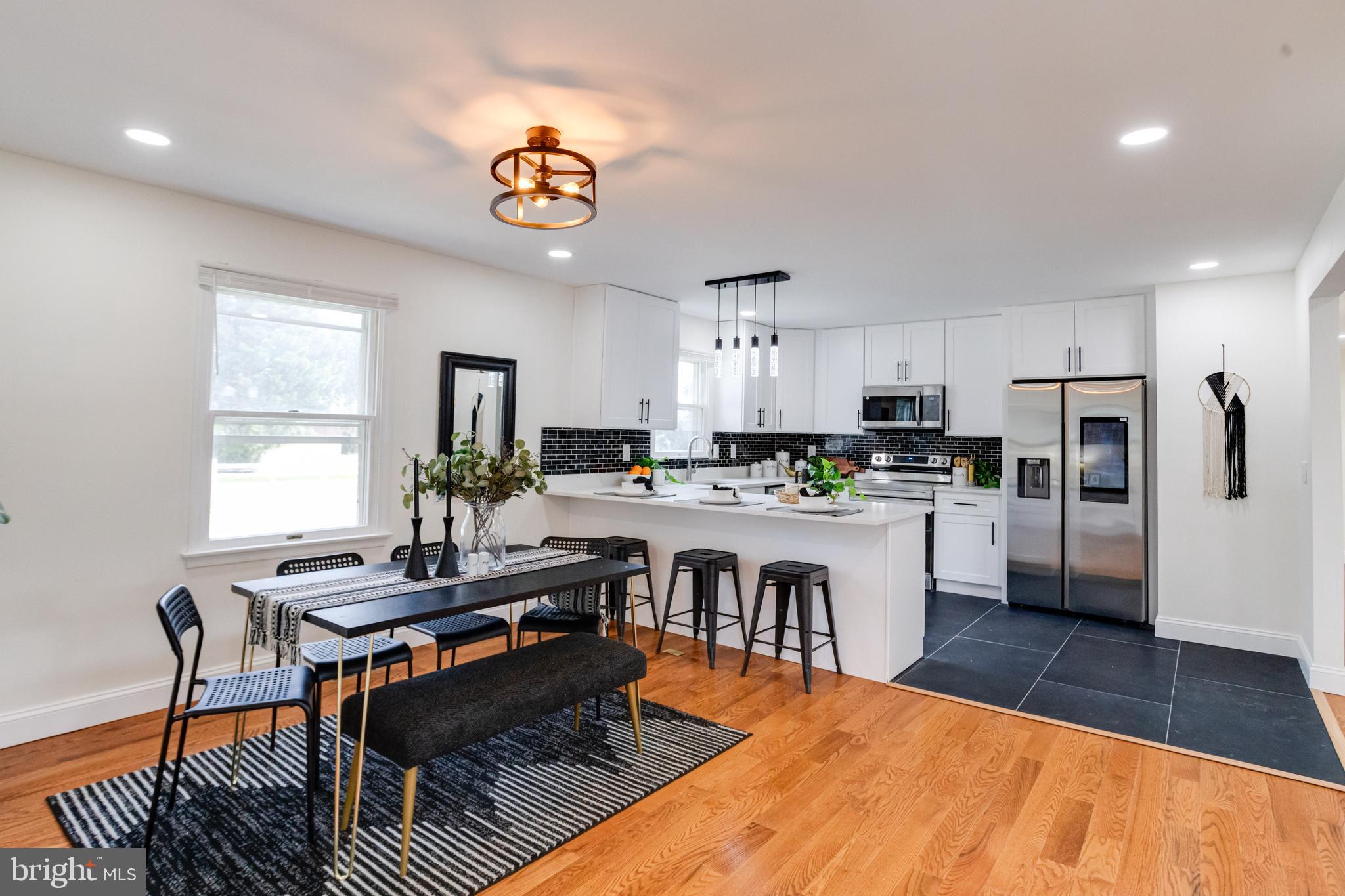 8041 Edgewater Avenue Rosedale, MD 21237 - Photo 4 of 38 a kitchen with stainless steel appliances granite countertop a stove top oven a sink dishwasher a dining table and chairs with wooden floor