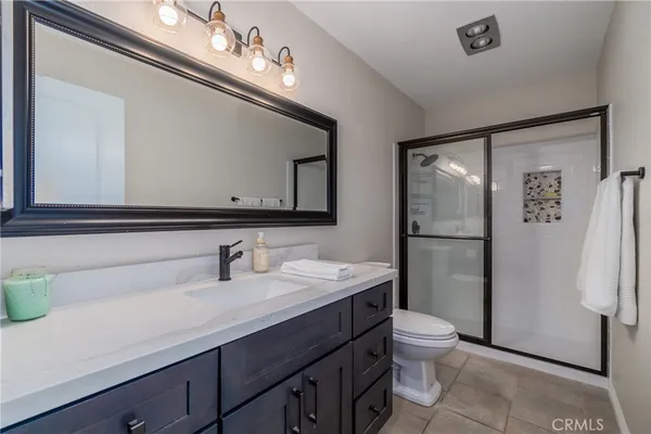 a bathroom with a sink a toilet a mirror and shower