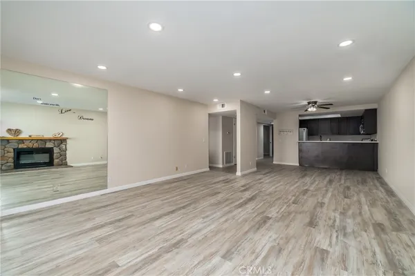 a view of an empty room and kitchen with a sink oven cabinets