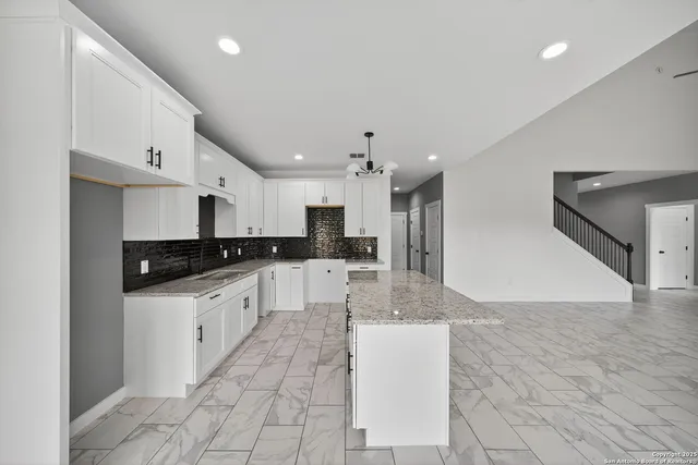 a large kitchen with stainless steel appliances kitchen island granite countertop a sink and a refrigerator