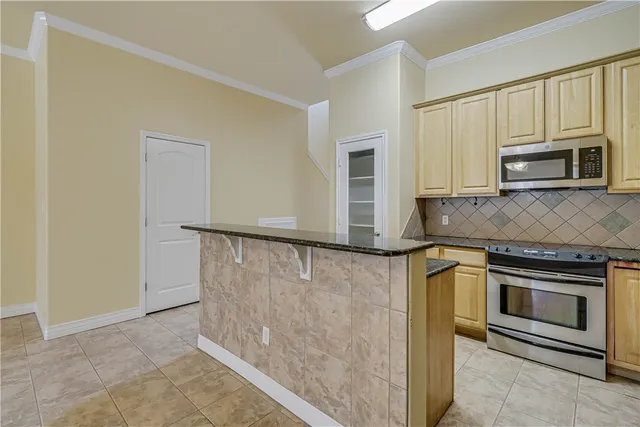 a kitchen with granite countertop cabinets stainless steel appliances and a counter space