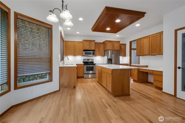 a kitchen with stainless steel appliances granite countertop wooden floors a stove a sink and a refrigerator