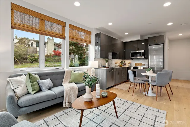a living room with furniture kitchen and a large window