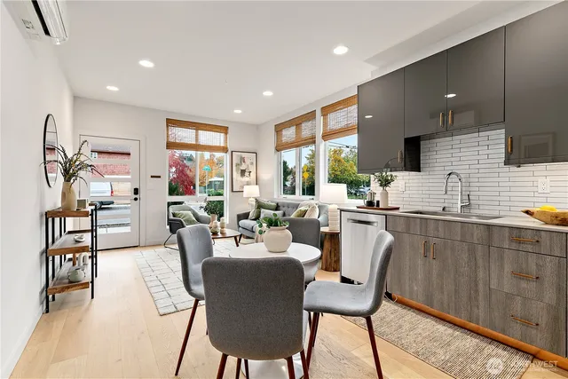 a very nice looking dining room with kitchen island stainless steel appliances furniture a large window and a sink