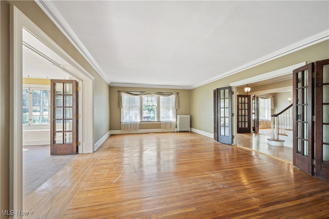 24510 Lake Road Bay Village, OH 44140 - Photo 9 of 45 Unfurnished room featuring french doors, crown molding, stairway, light wood finished floors, and radiator