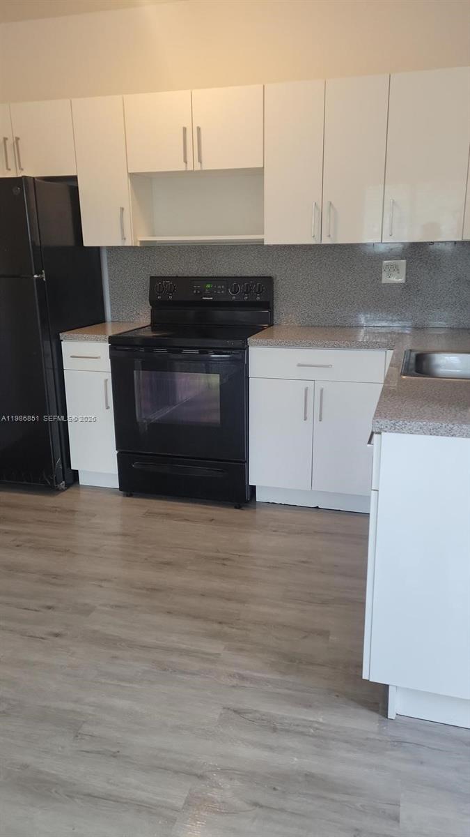 a kitchen with granite countertop a stove top oven a sink and white cabinets
