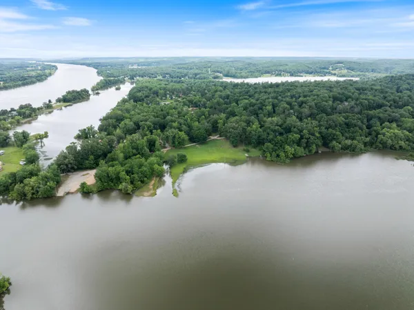 an aerial view of green landscape with trees houses and lake view