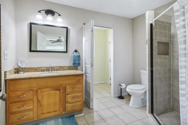 a bathroom with a granite countertop sink a mirror and a toilet
