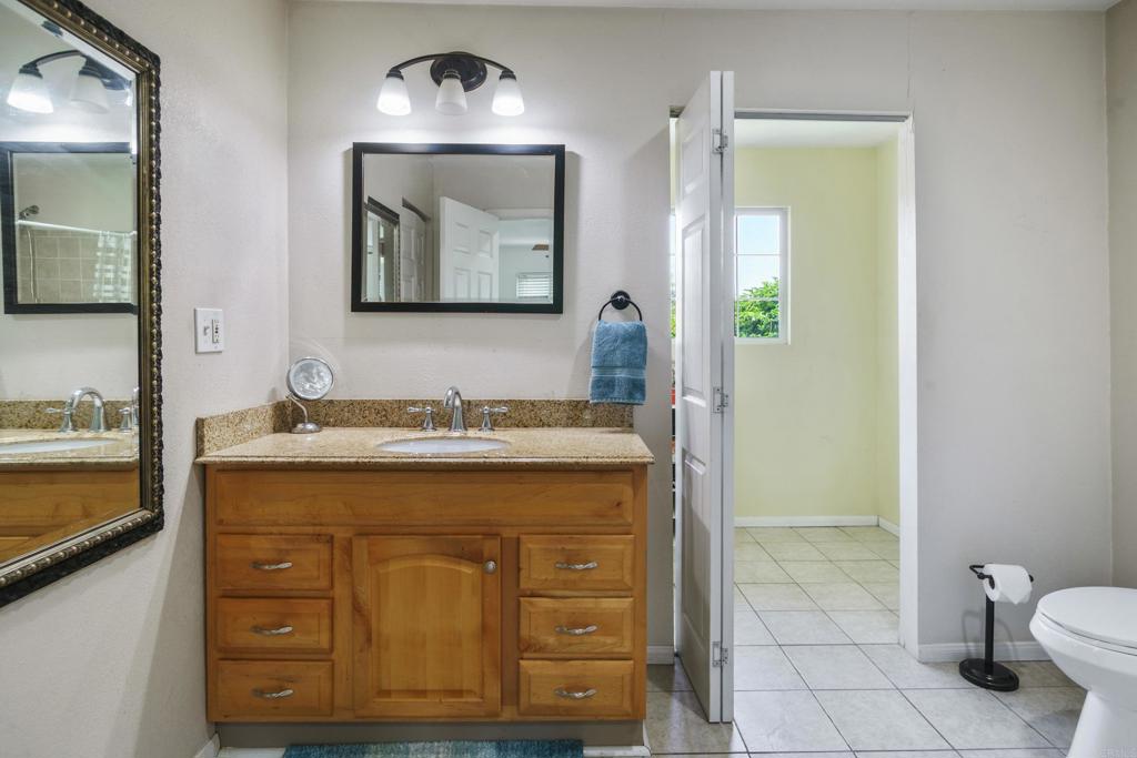306 Fowles Street Oceanside, CA 92054 - Photo 19 of 29 a bathroom with a granite countertop sink a mirror and a toilet