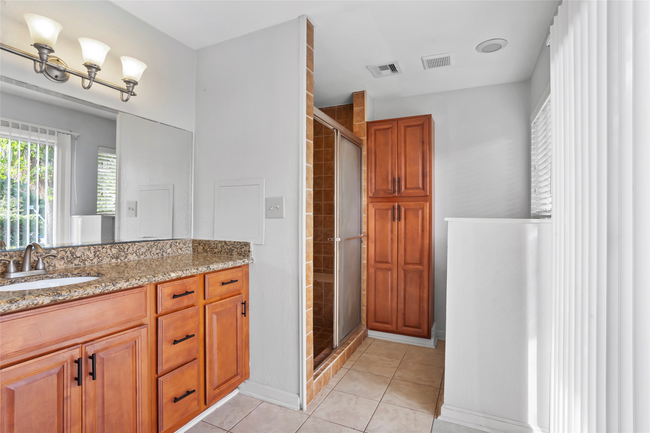 16 Harbor Lane Kemah, TX 77565 - Photo 19 of 31 a bathroom with a granite countertop sink a mirror a vanity and a shower