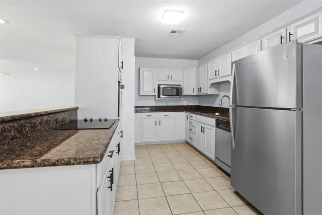 a kitchen with stainless steel appliances granite countertop a refrigerator a sink dishwasher a stove with white cabinets