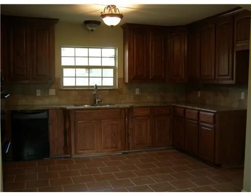 a kitchen with granite countertop a stove a sink and a window