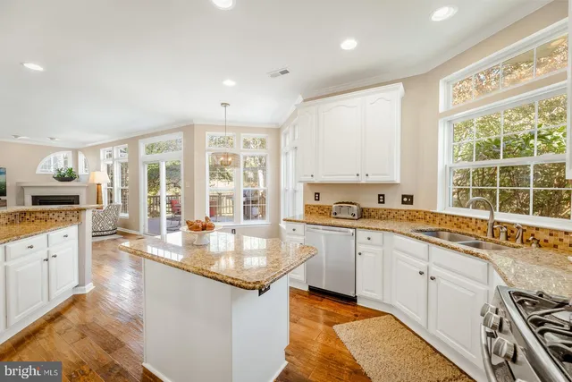 a large kitchen with granite countertop a large window and white cabinets