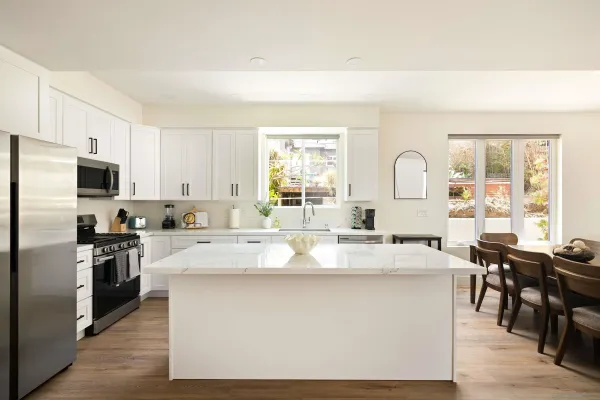 a large kitchen with kitchen island white cabinets and stainless steel appliances