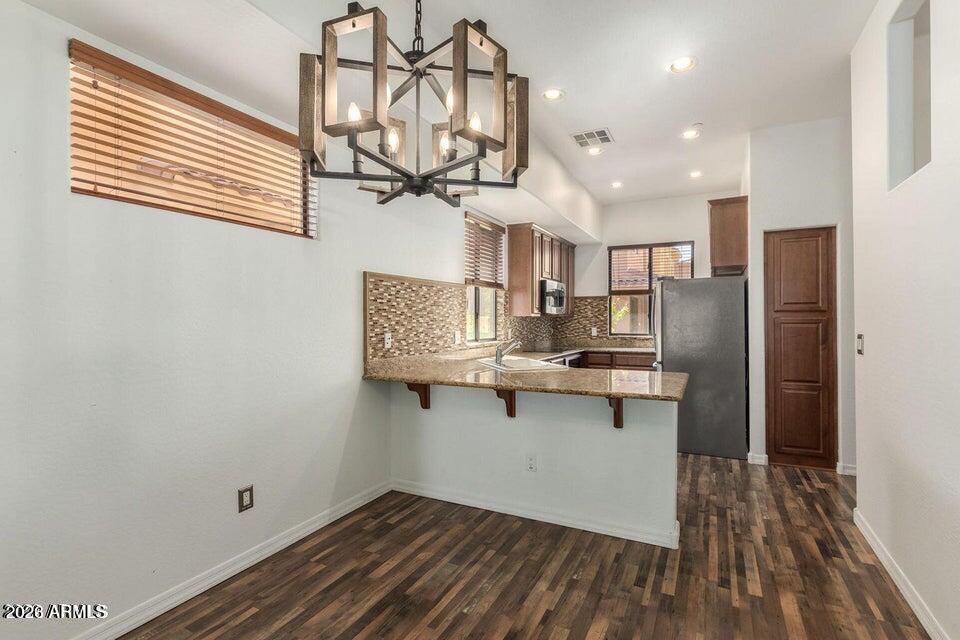 9551 East Redfield Road, Unit 1008 Scottsdale, AZ 85260 - Photo 9 of 19 a kitchen with stainless steel appliances a wooden floor and white cabinets