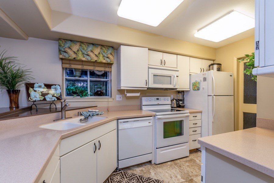 68-1745 Waikoloa Road, Unit L101 Waikoloa, HI 96738 - Photo 6 of 27 a kitchen with white cabinets and white appliances