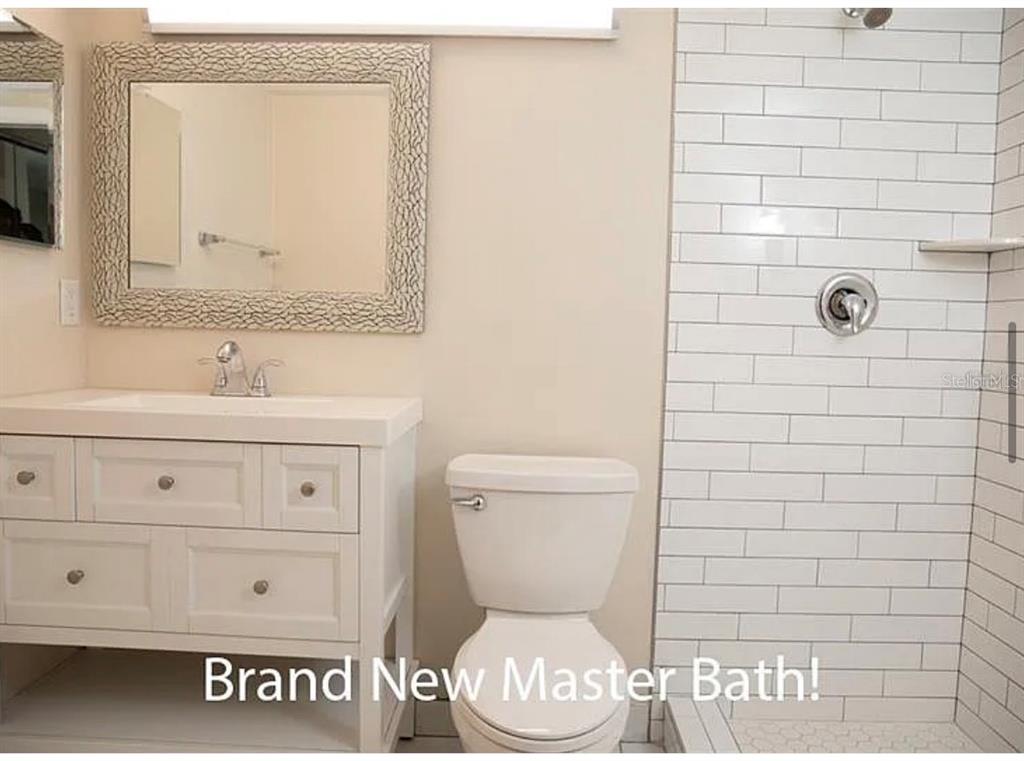 1724 Pine Ridge Way West, Unit B1 Palm Harbor, FL 34684 - Photo 12 of 12 a bathroom with a toilet sink vanity and mirror