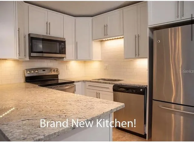 a kitchen with granite countertop a refrigerator stove and microwave