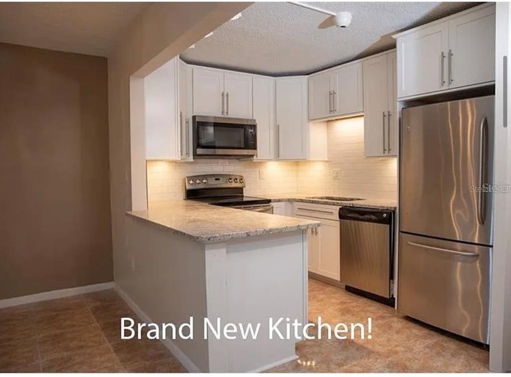 1724 Pine Ridge Way West, Unit B1 Palm Harbor, FL 34684 - Photo 9 of 12 a kitchen with granite countertop a refrigerator stove and microwave