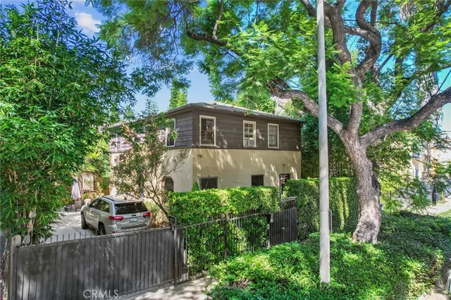 a view of a small yard in front of a house with large trees and plants