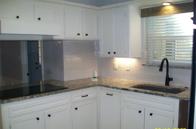 a kitchen with granite countertop white cabinets and a sink