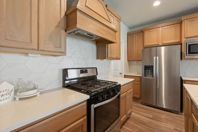 a kitchen with stainless steel appliances granite countertop a stove a refrigerator and a sink
