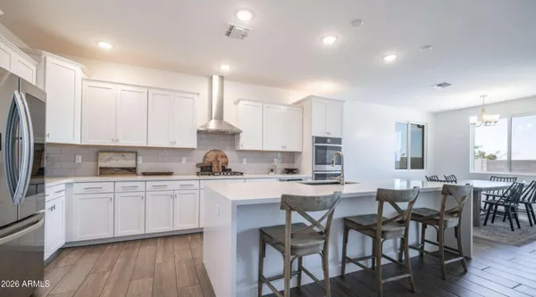 a kitchen with stainless steel appliances granite countertop a table chairs sink refrigerator and cabinets