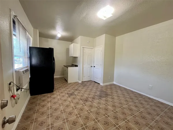 a view of a refrigerator in kitchen and an empty room