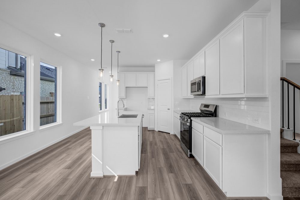22122 Strathfield Circle Cypress, TX 77433 - Photo 2 of 38 a kitchen with stainless steel appliances kitchen island wooden floors and white cabinets