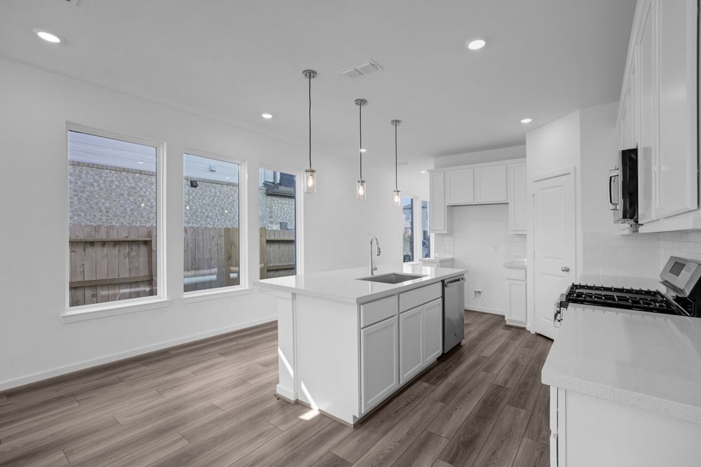 22122 Strathfield Circle Cypress, TX 77433 - Photo 4 of 38 a large white kitchen with a large window a sink and stainless steel appliances