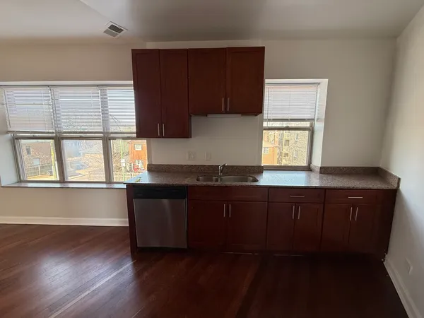 a kitchen with granite countertop wooden cabinets a sink and a window
