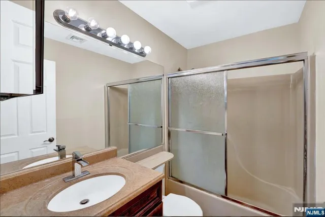 a bathroom with a granite countertop shower sink vanity and a mirror