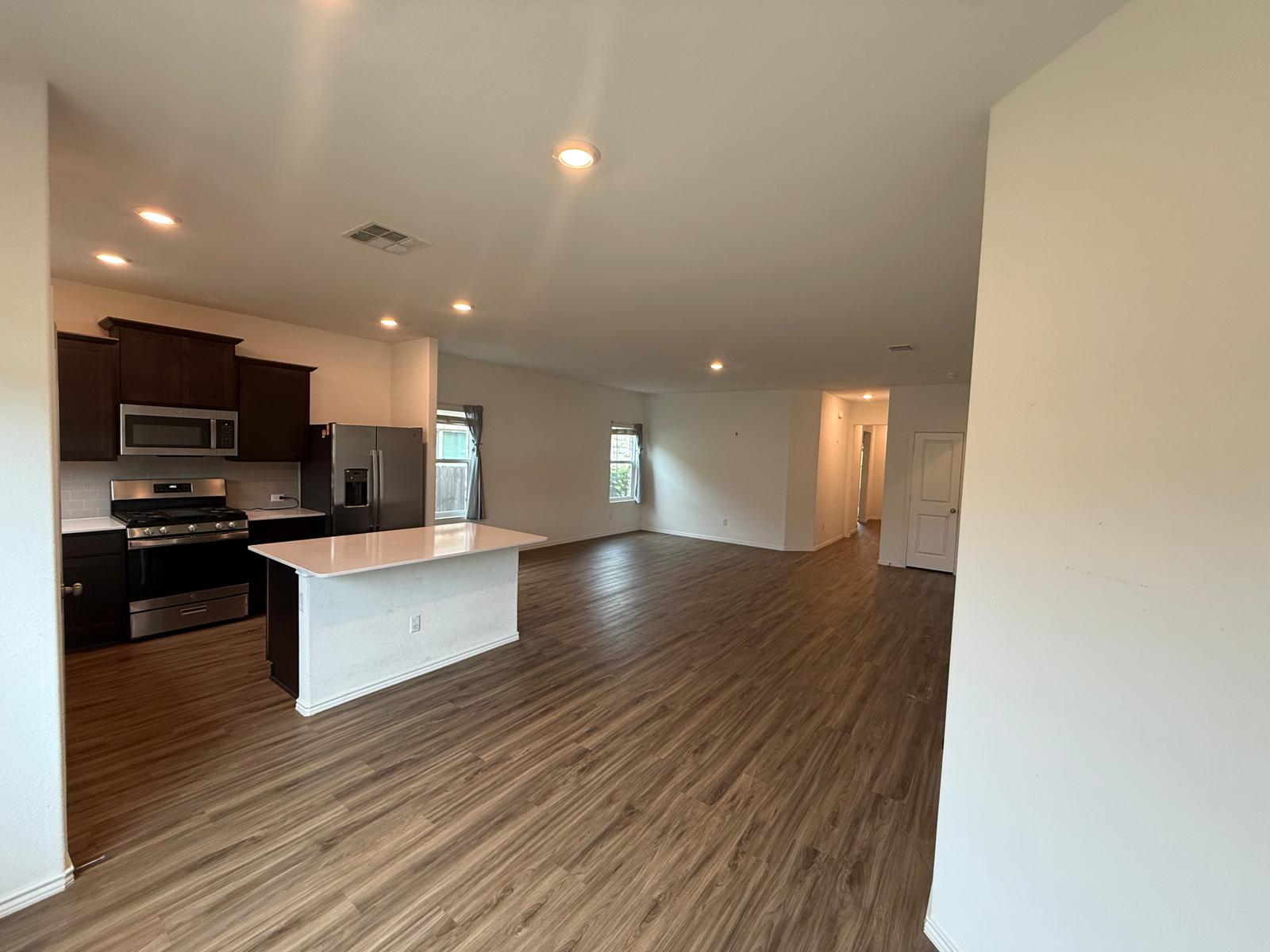 1521 Brueggerhoff Road Leander, TX 78641 - Photo 5 of 15 Gleaming wood-look floors anchor a sweeping, open layout connecting the kitchen and living areas.