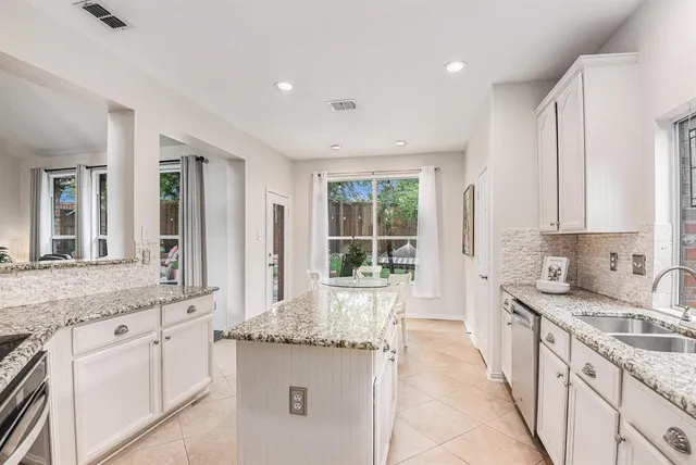 a large white kitchen with granite countertop a sink and dishwasher with a large window