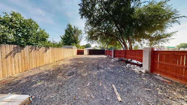 a backyard of a house with wooden fence and large trees