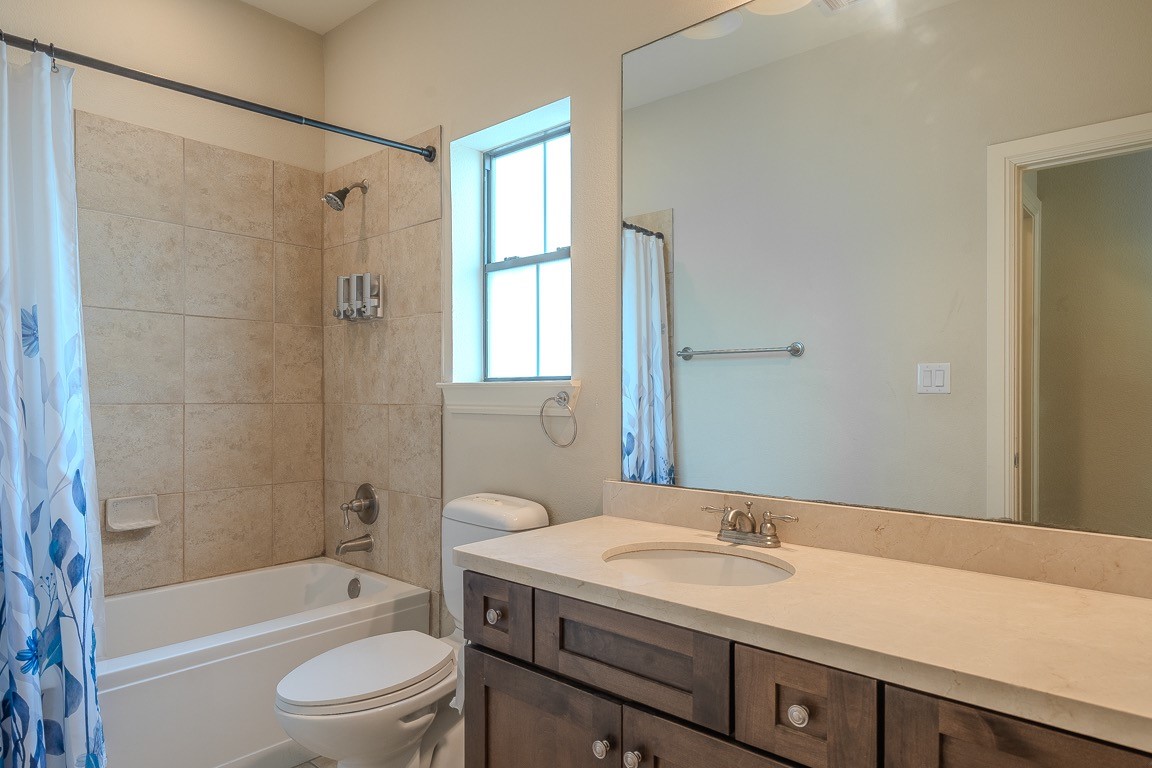 5213 Eigel Street, Unit B Houston, TX 77007 - Photo 23 of 28 a bathroom with a granite countertop sink a toilet a mirror a bathtub and shower