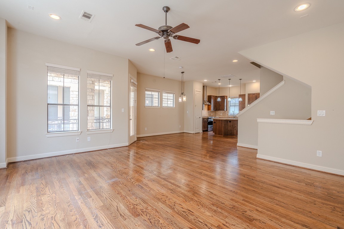 5213 Eigel Street, Unit B Houston, TX 77007 - Photo 5 of 28 an empty room with wooden floor a ceiling fan and kitchen view