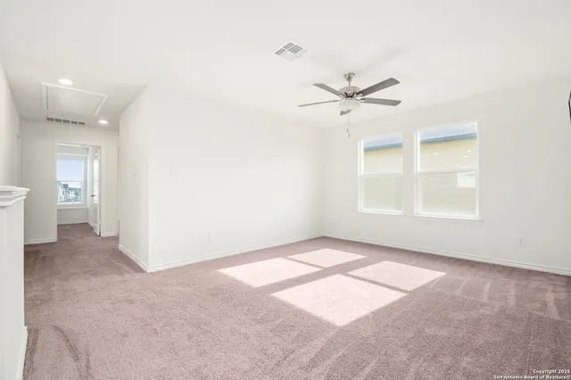 an empty room with chandelier fan and windows