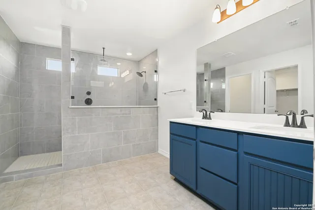 a bathroom with a double vanity sink mirror and shower