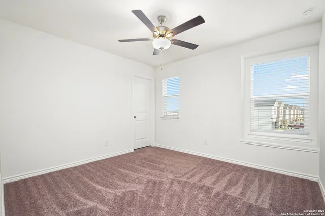 an empty room with a window and a ceiling fan