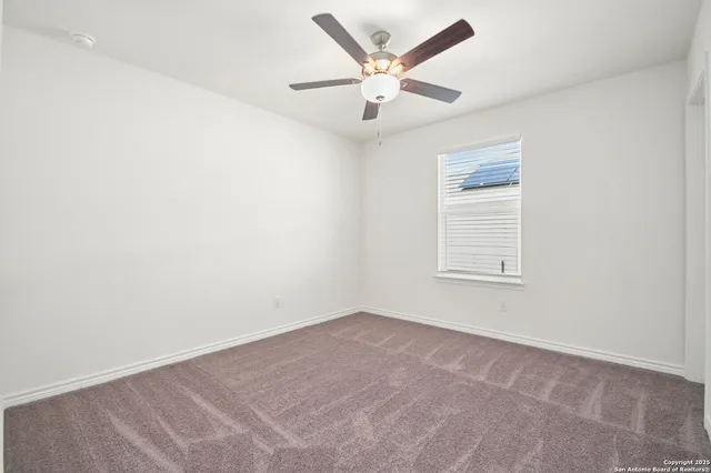 an empty room with a ceiling fan and window