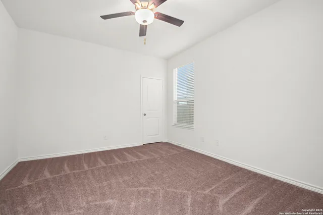 an empty room with a chandelier fan and windows