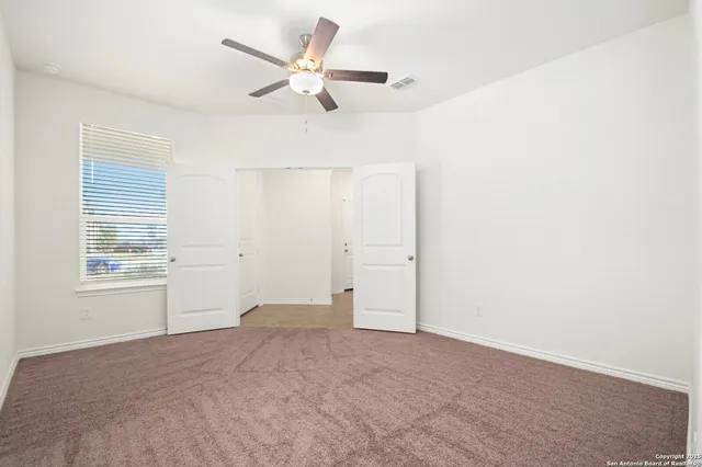 an empty room with windows and fan