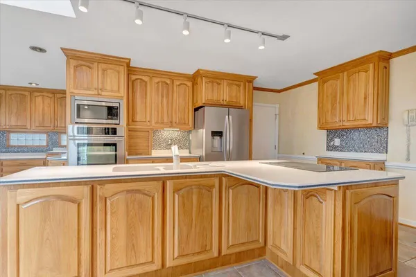 a large white kitchen with granite countertop a sink and white cabinets next to a window