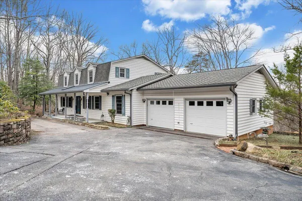 a view of a white house with a large tree and wooden fence